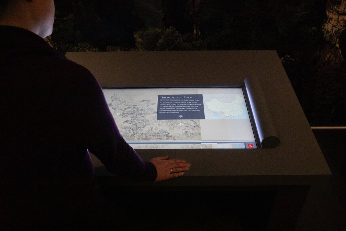 Visitors using Chinese handscroll display Museum learning through interactivity
