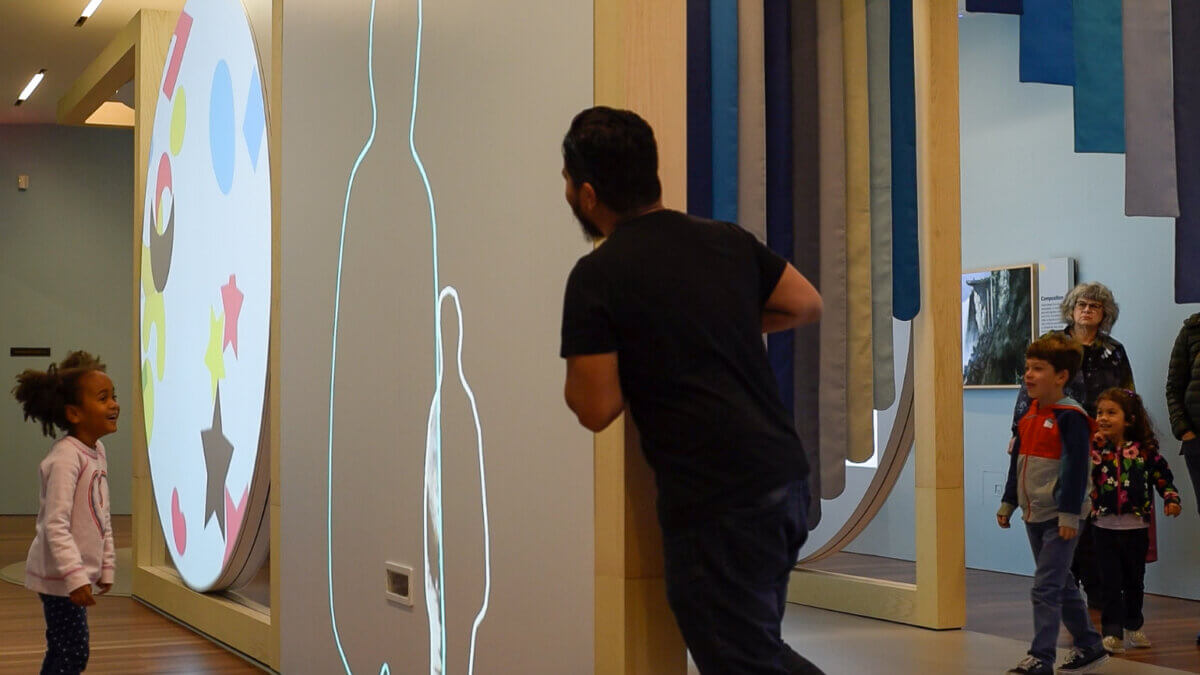 Family enjoying free creative play space for experiential futures with kids playing with color and light